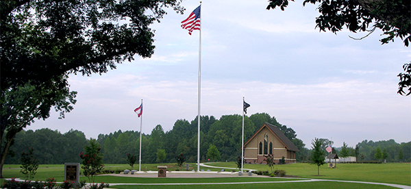 GVMC-Glennville's committal shelter is set on a flat green lawn, with three flag staffs in a gathering area in front. 