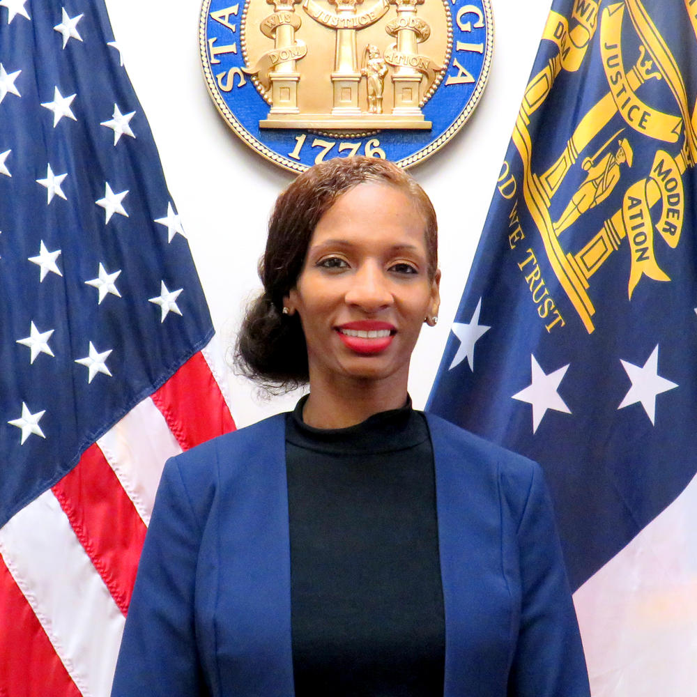 Takosha Swan stands in front of the US flag and Georgia flag.